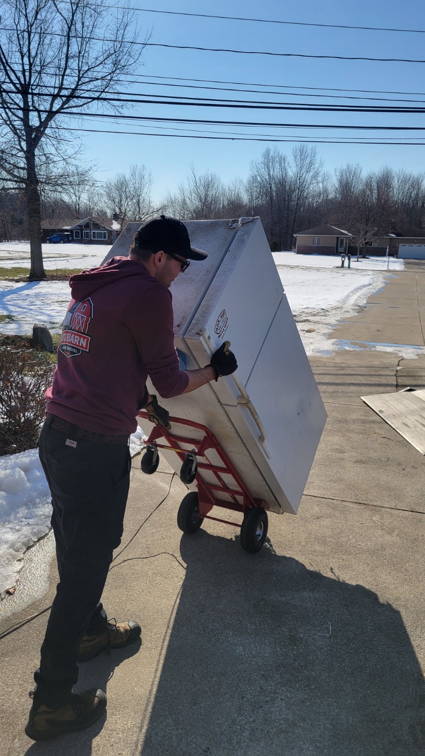 Big Barn Junk Removal team moving a large appliance with a dolly for removal