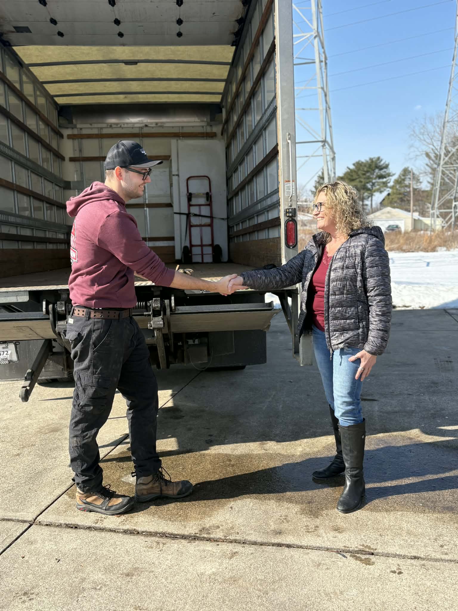 Big Barn Junk Removal team member shaking hands with a customer near the box truck